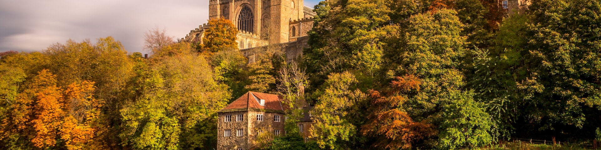 A historic cathedral, a stone building, and a river with a waterfall.