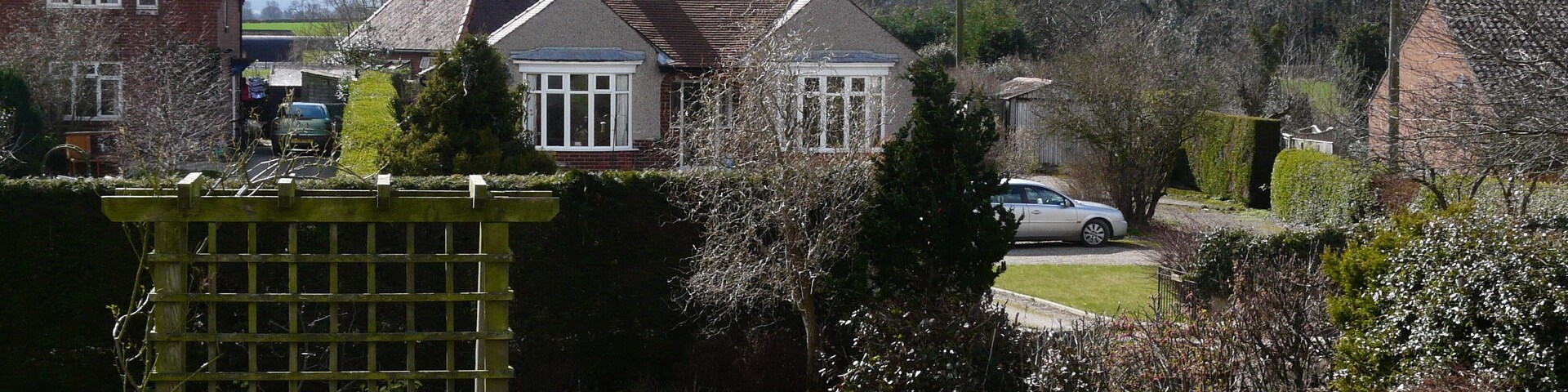 A residential area with houses, a garden, and a white car parked on the street.