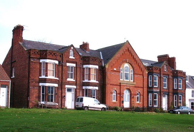 A row of red brick houses with white trim and multiple windows.