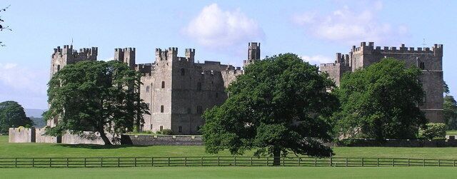 A large castle with multiple towers and a surrounding fence.