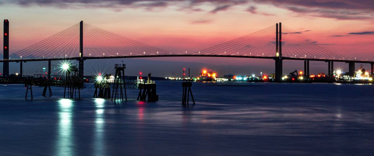 A bridge at dusk with lights reflecting on the water.