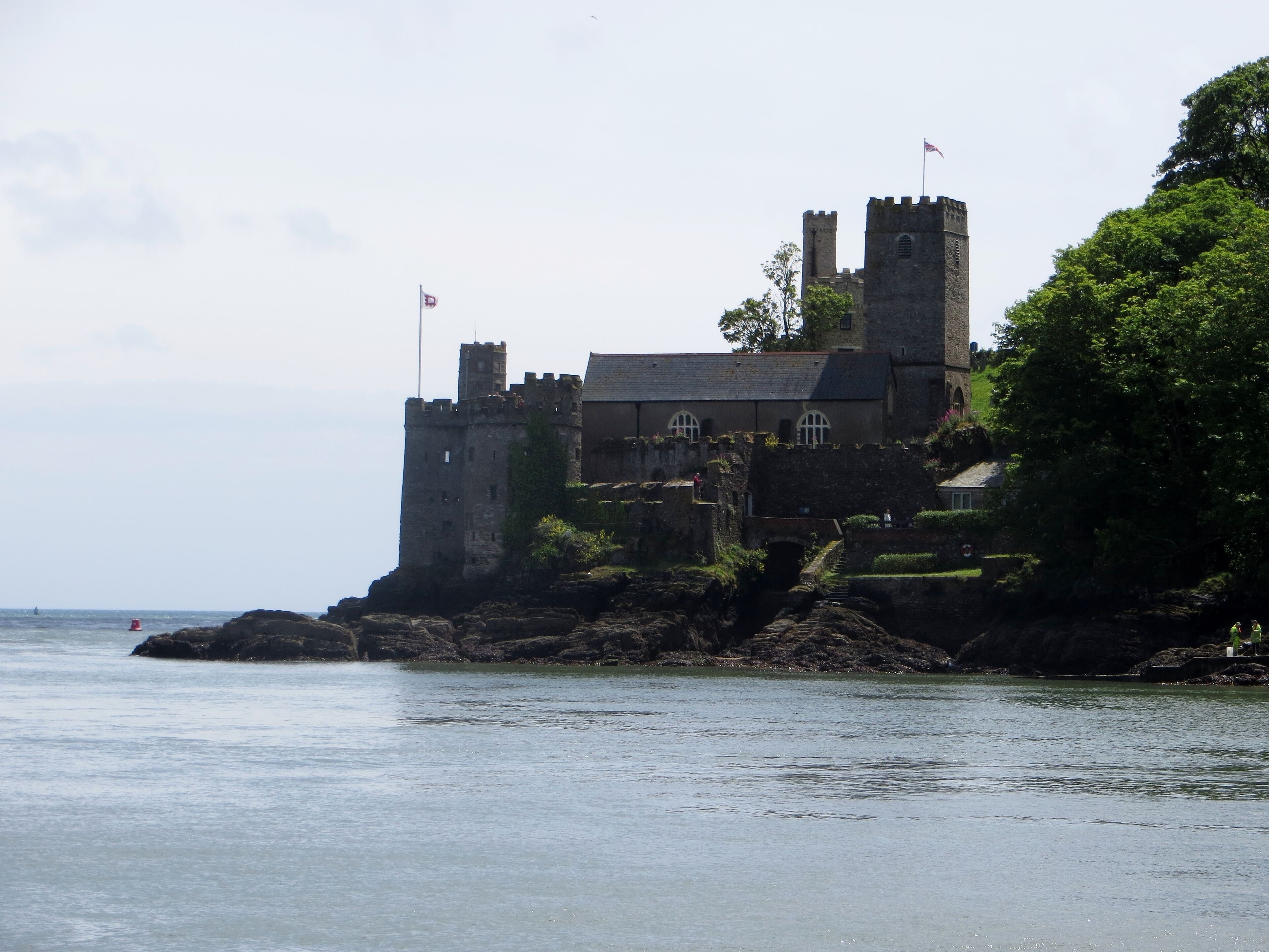 A castle on a rocky coastline with a flag on top.
