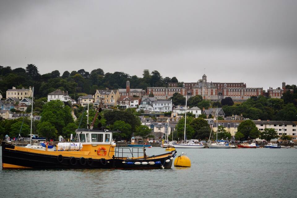 A harbor with a yellow tugboat named HAULEY-IV, surrounded by various buildings and trees.