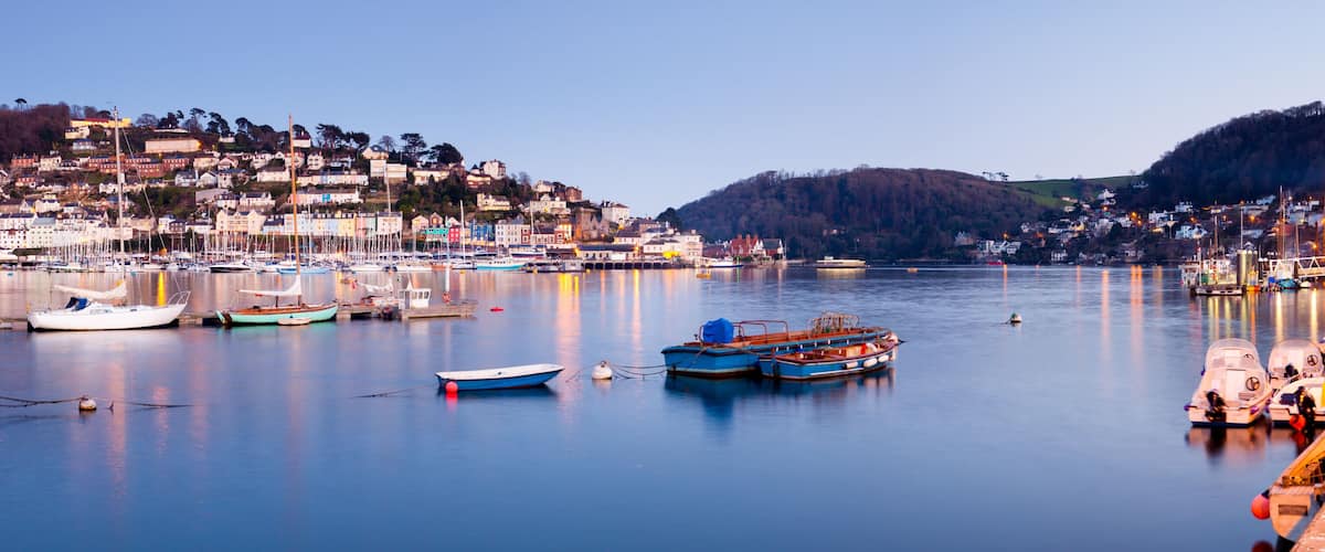 A harbor with boats, a waterfront promenade, and a hillside settlement.