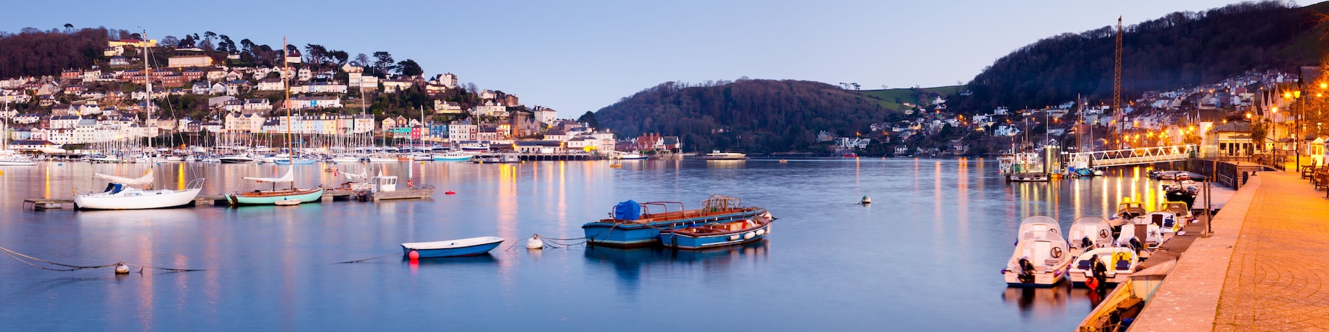 A harbor with boats, a waterfront promenade, and a hillside settlement.