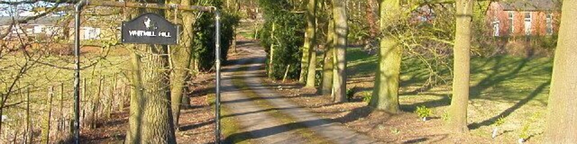 Un sendero en un parque con un cartel que dice 'Whittingham Hill'.