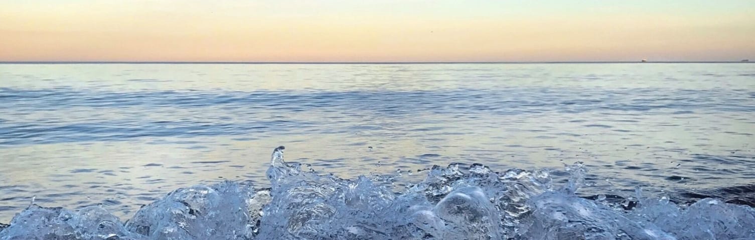 Ein Strand mit brechenden Wellen und blauem Himmel.