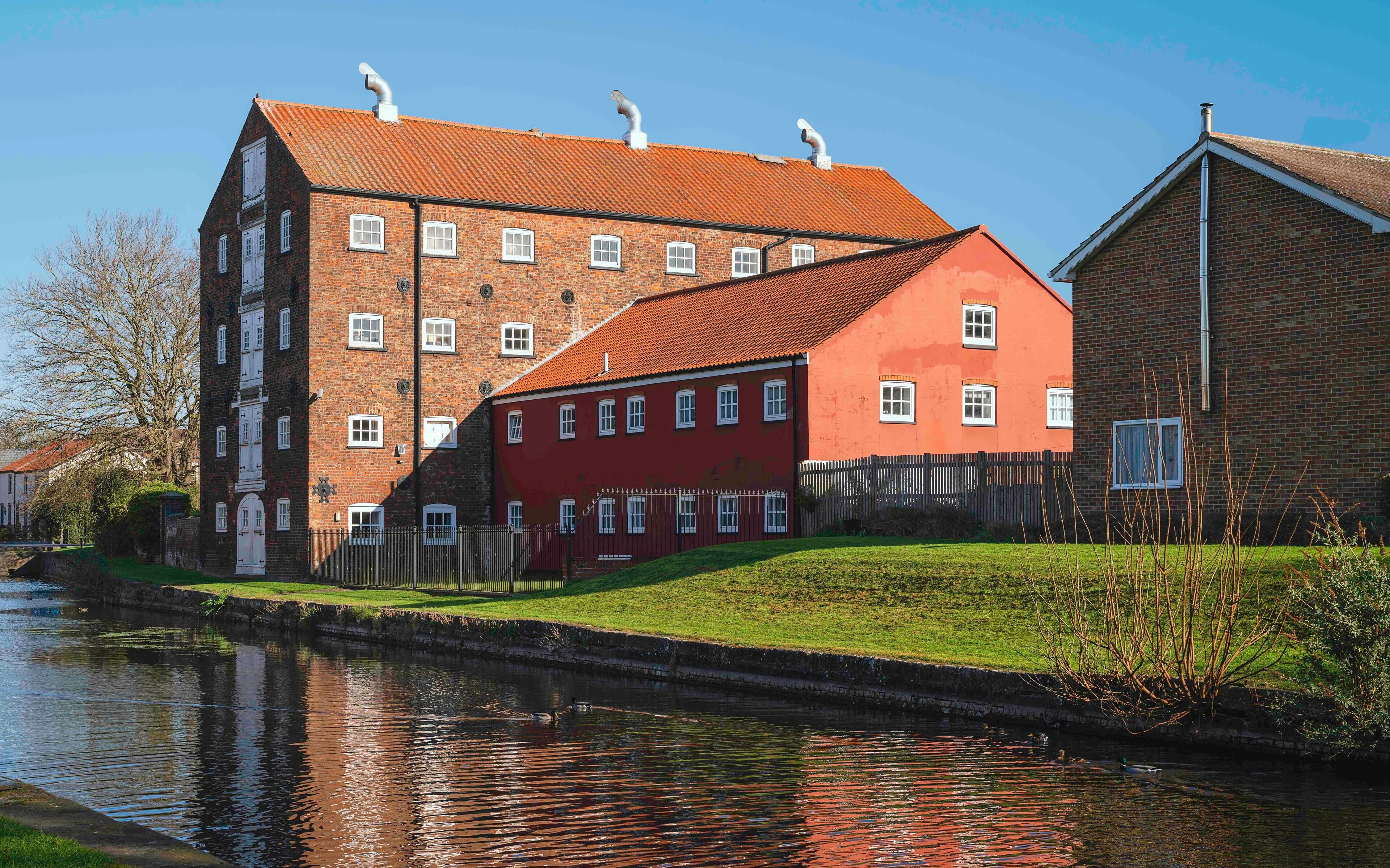 A canal with a red building and a brick building with a red roof.