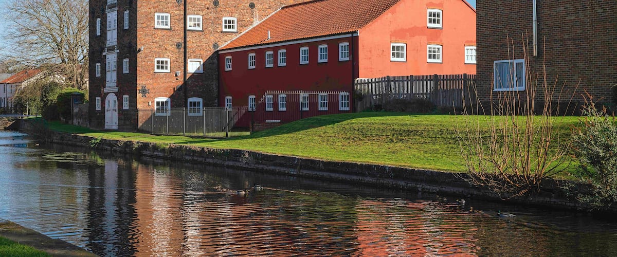 A canal with a red building and a brick building with a red roof.