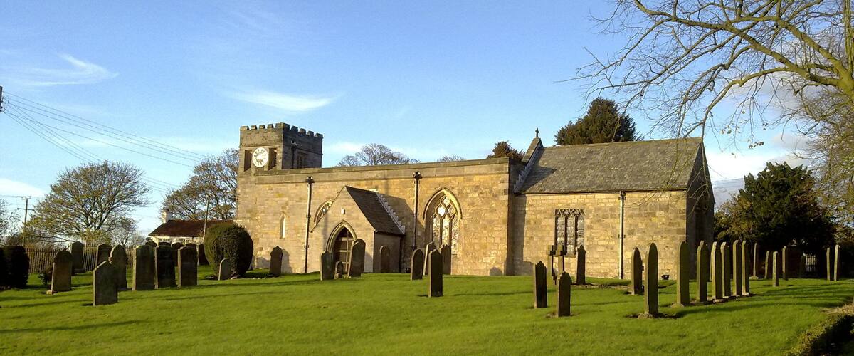 A church with a clock tower and a graveyard.