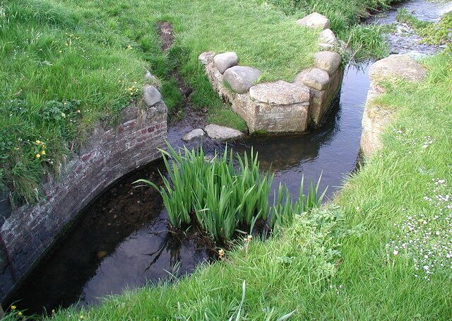 Spittle Beck Sheep Dike, Nafferton, East Riding of Yorkshire, England. Disused sheep wash on Spittle Beck at the corner of Wansford Road and New Bridge Road, Nafferton. When in use, the water level would have been controlled by a sluice gate while a farm hand stood in a wooden tub in the beck to wash the sheep. The sheep would be dumped in one at a time and given a good rubbing in the chemical-free water to try to get a reasonably clean fleece before shearing. The sheep wash fell into disuse in around 1940 but was restored by Nafferton Scout Group in 1991.