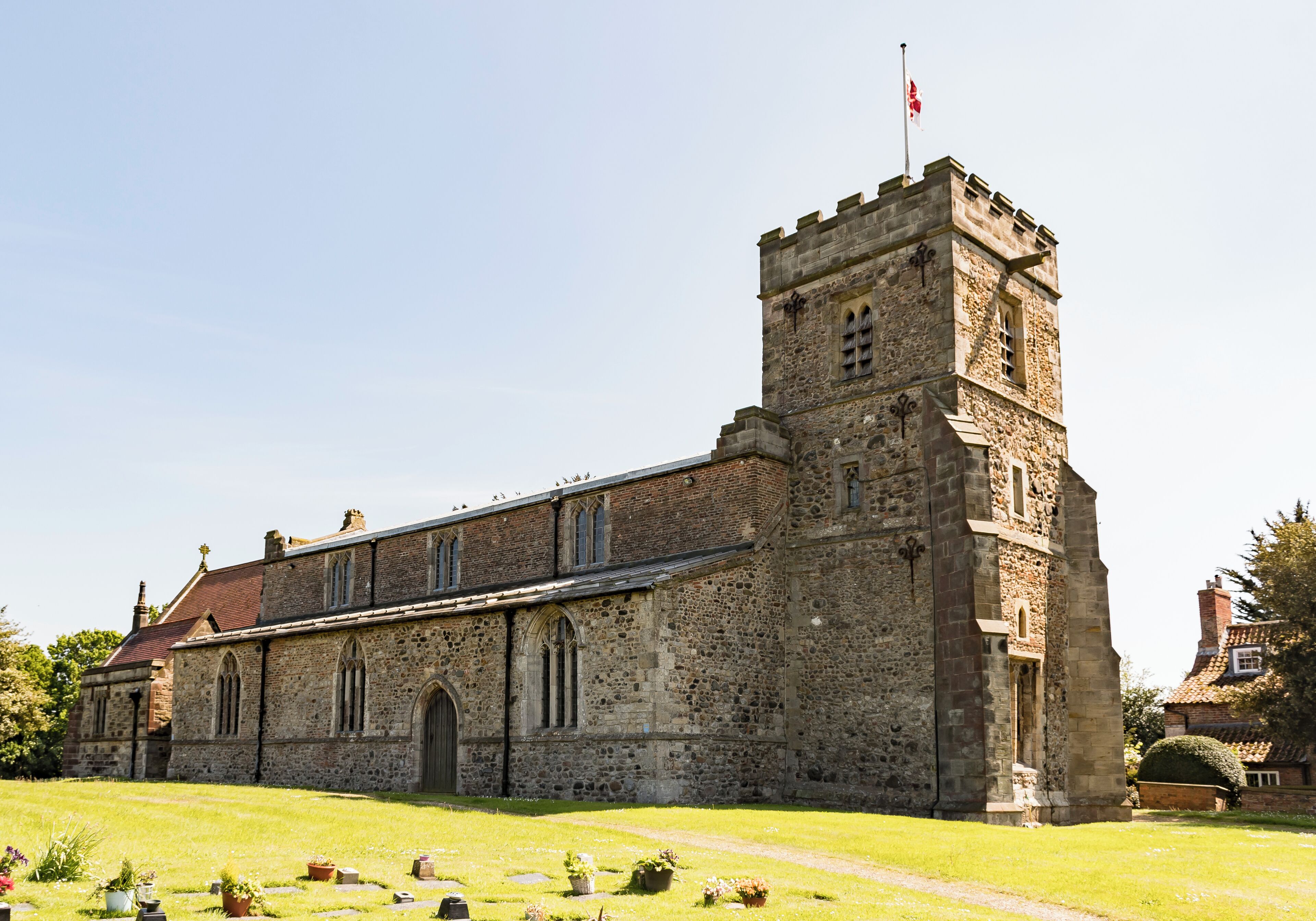 A historic stone church with a prominent tower and a flag on top.