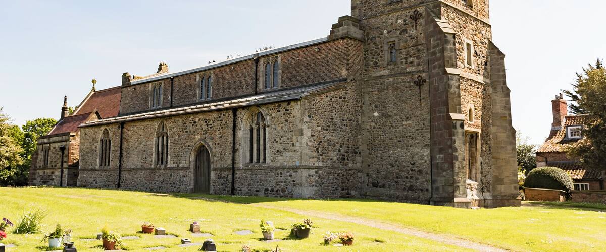 A historic stone church with a prominent tower and a flag on top.