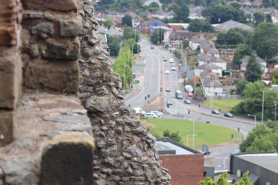 A stone wall with a view of a cityscape in the background.