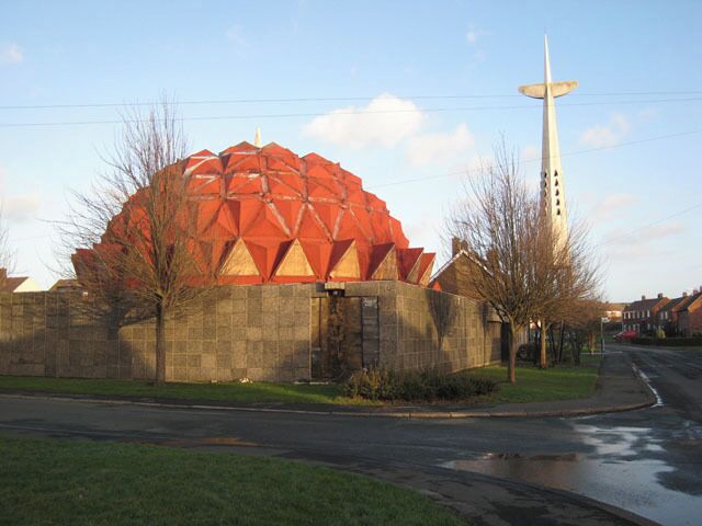 A large red geodesic dome building with a tall white spire in the background.