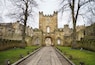 A historic stone building with a central tower, arched windows, and a cobblestone pathway leading to the entrance.