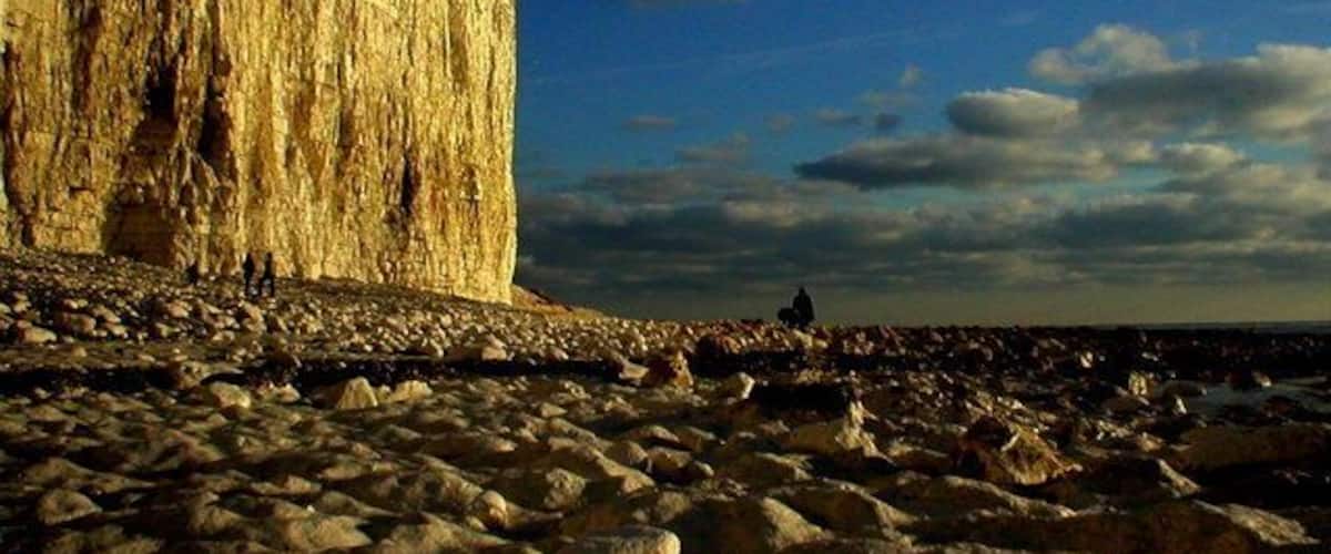 A rocky beach with a large cliff in the background.