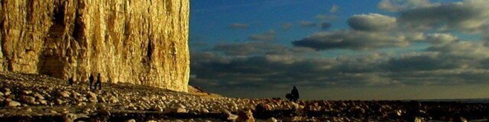 Una playa rocosa con un gran acantilado al fondo.