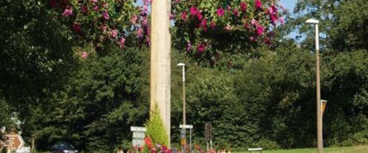 Een bord met de tekst 'East Grinstead', omringd door bloemen en begroeiing.