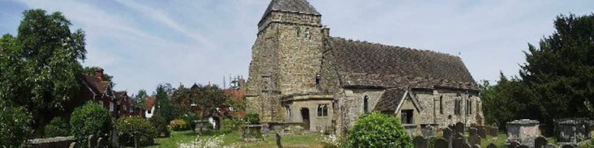 Eine Kirche mit einem hohen Turm, umgeben von einem Friedhof mit Grabsteinen.