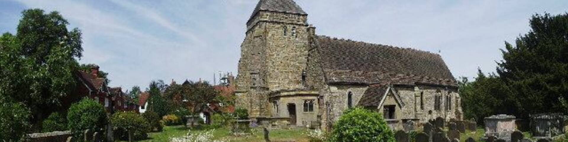 A church with a tall spire, surrounded by a cemetery with gravestones.