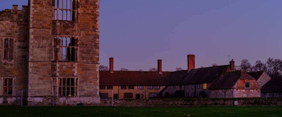 A historic stone tower and traditional buildings under a twilight sky.