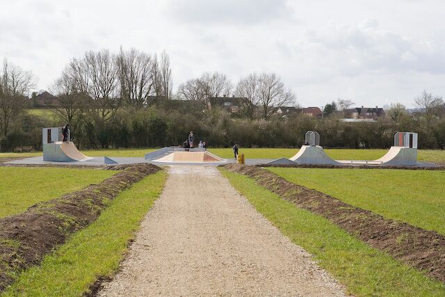 A skate park with ramps and a gravel path.