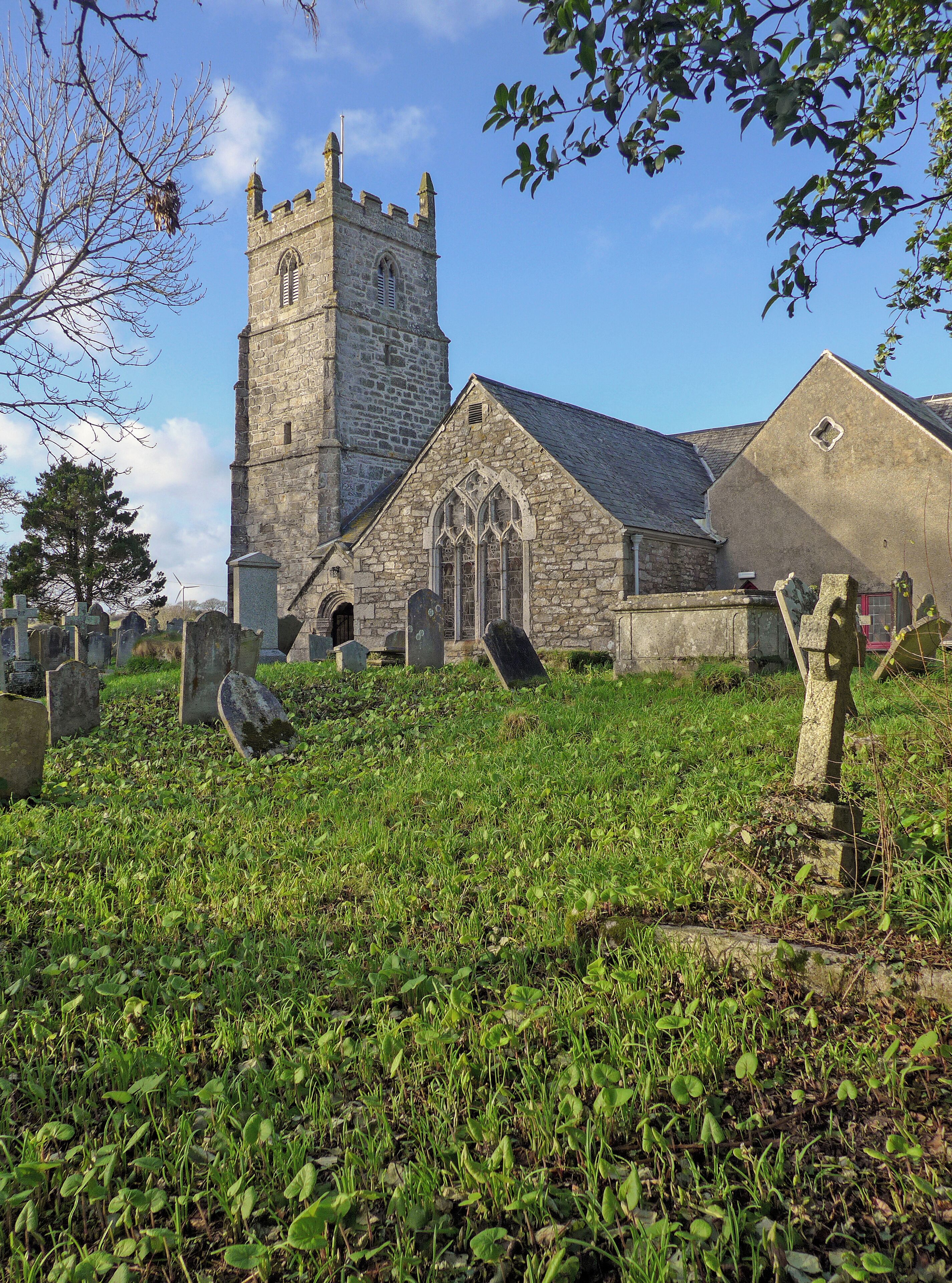A historic church with a tall tower and Gothic windows, surrounded by a cemetery with headstones.