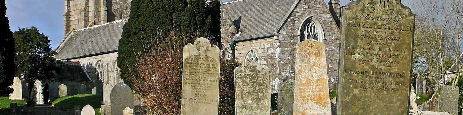 A church with a tall tower and a graveyard with headstones.