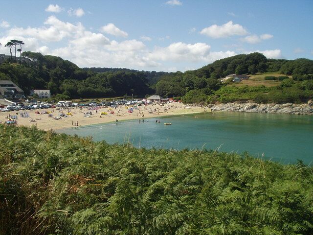 A beach with people, a sandy shore, and a body of water.