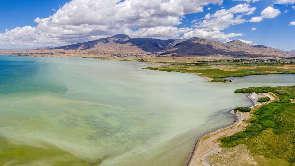 A coastal landscape with mountains, clear waters, and agricultural fields.