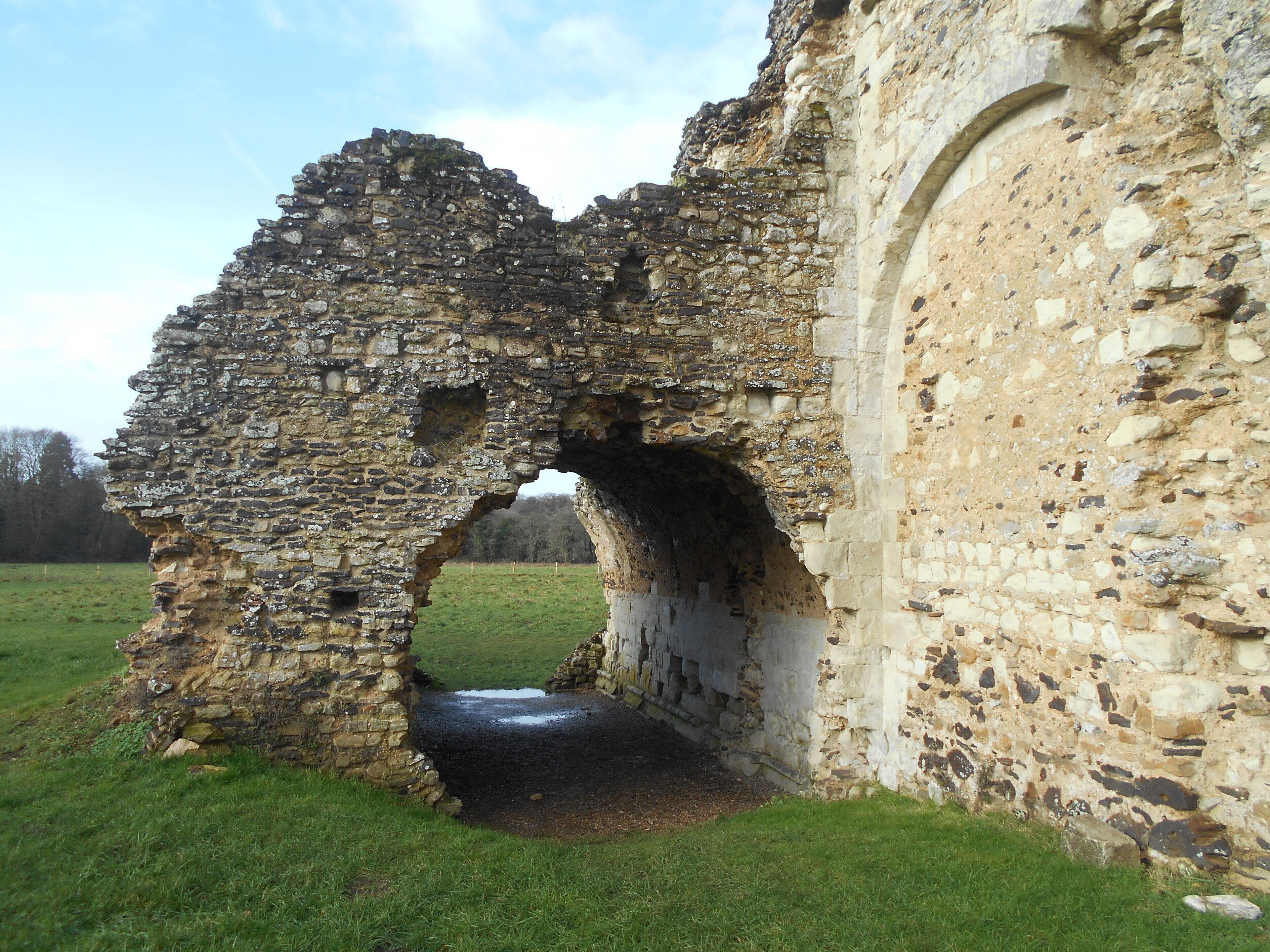 A stone archway leading into a grassy field, surrounded by stone walls.