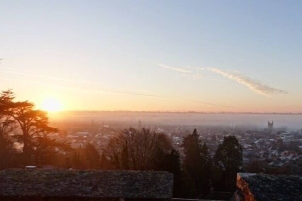 A sunrise over a cityscape with a distant tower.