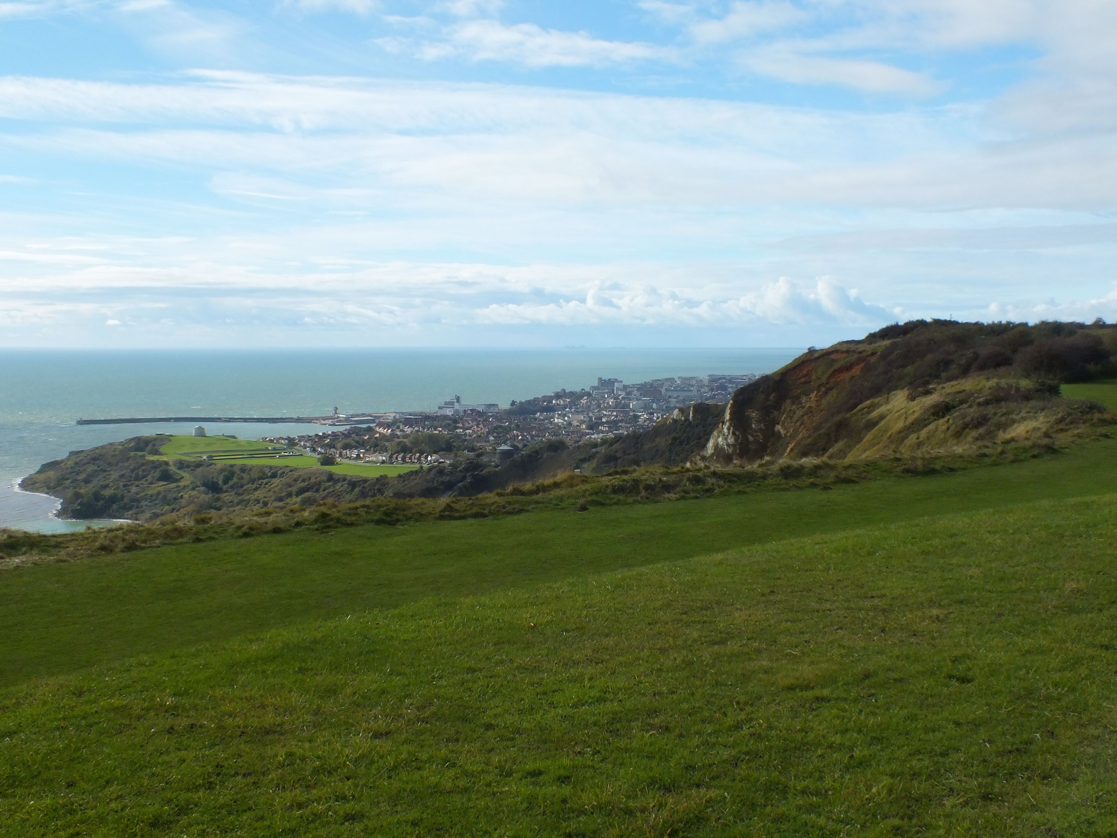 A coastal landscape with a town, cliffs, and a lighthouse.