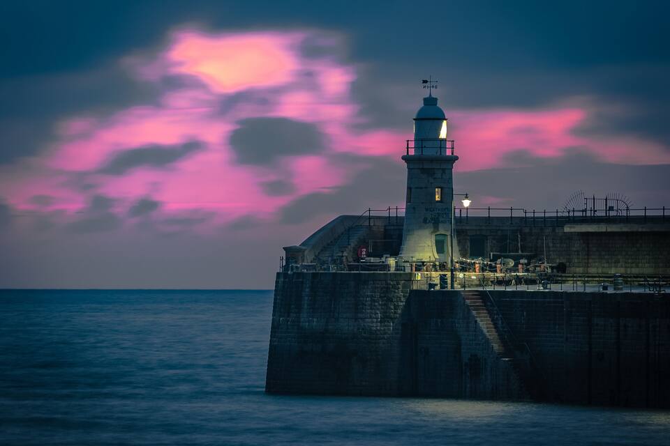 Un phare au crépuscule, avec un ciel rose.