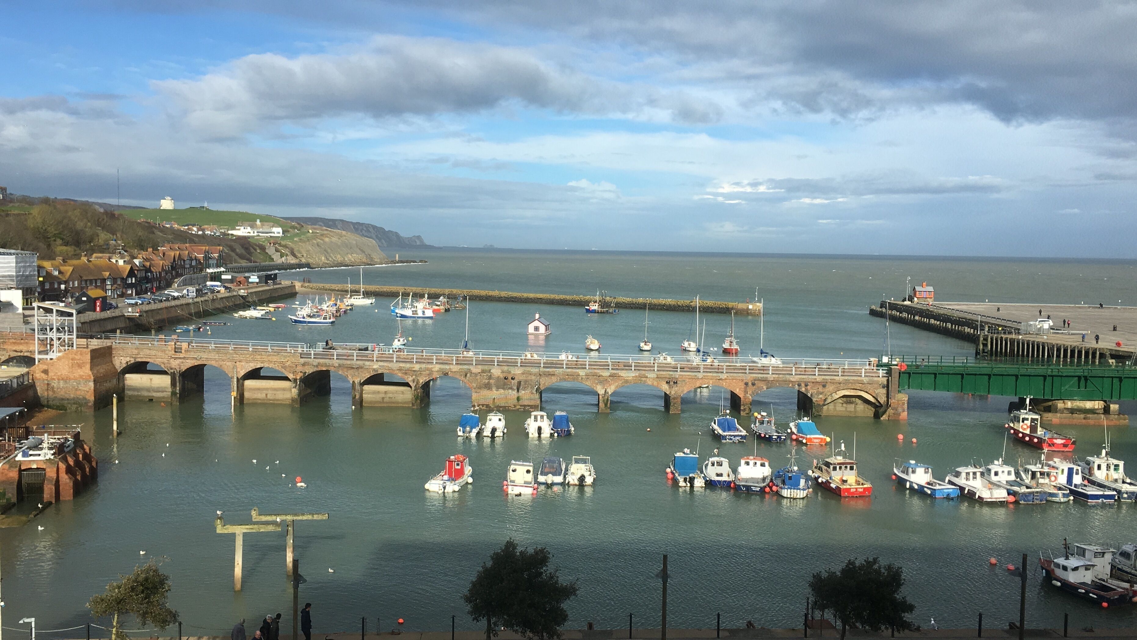 A harbor with a bridge, boats, and a lighthouse.