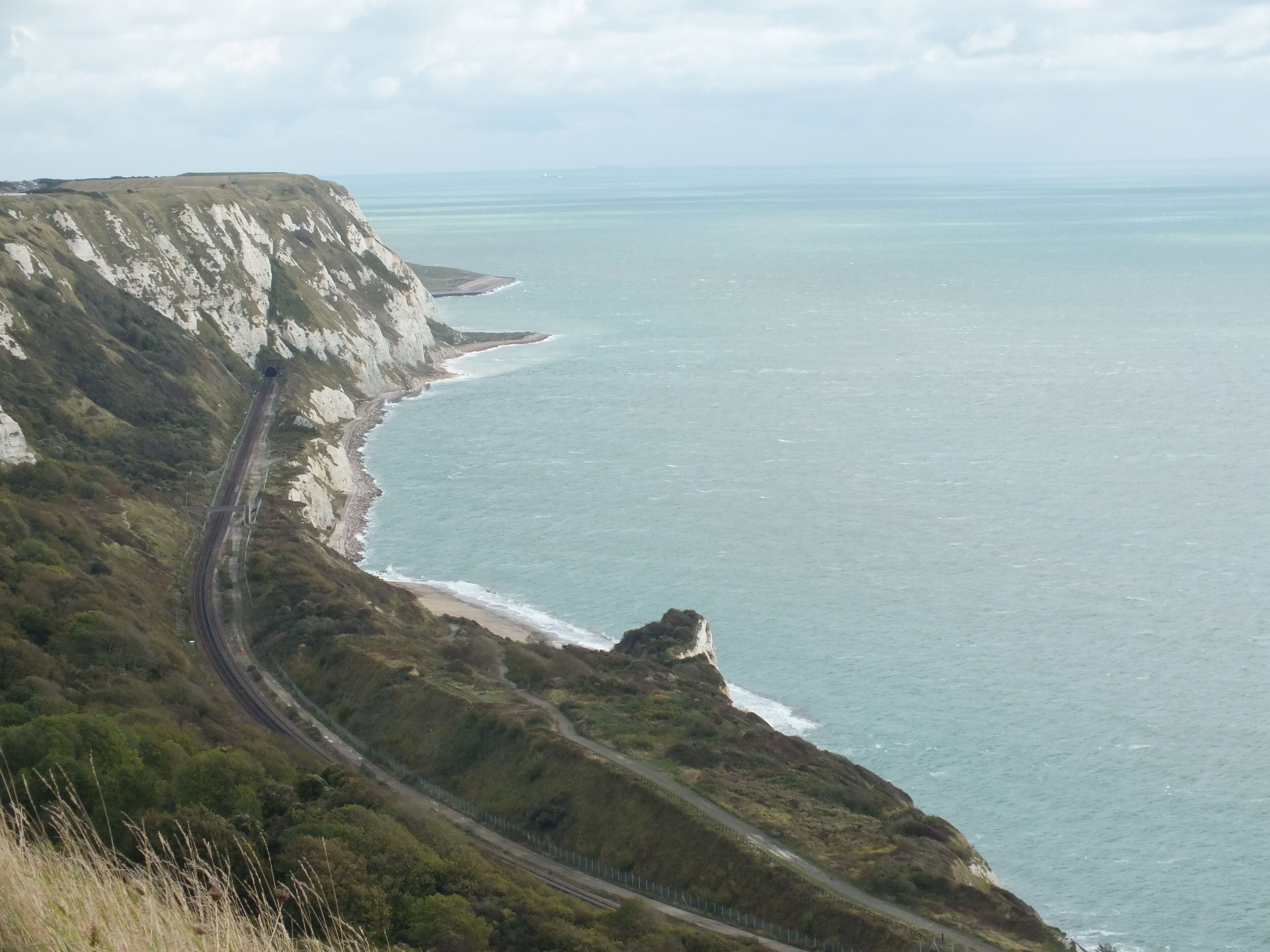 A coastal road winding along cliffs, overlooking the sea.