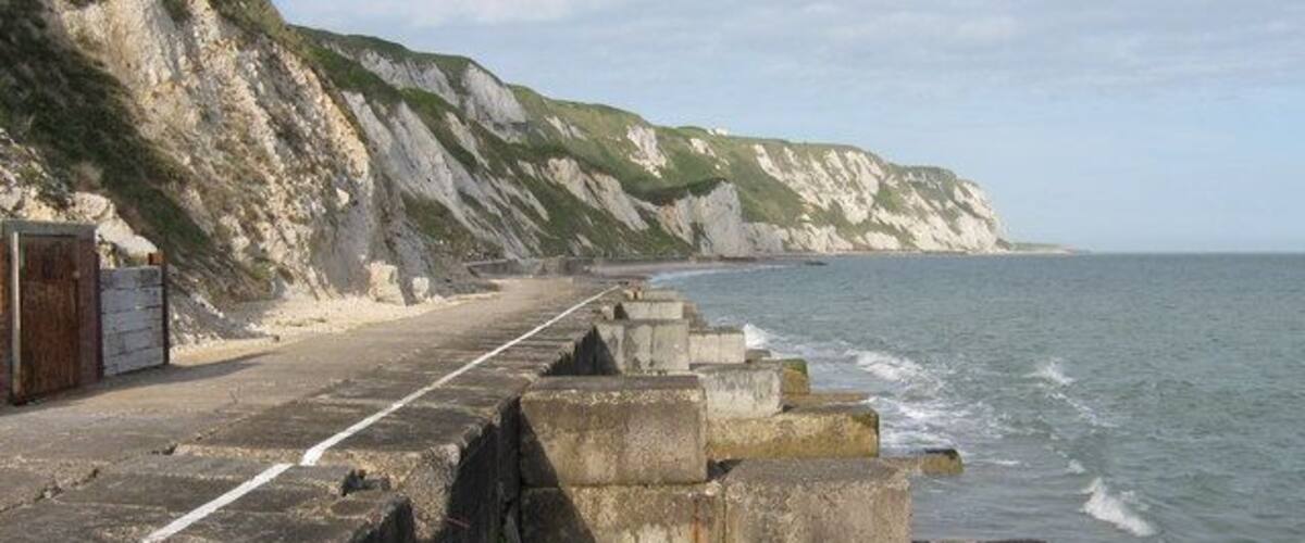 Une route côtière bordée de murs de protection en béton et de falaises.