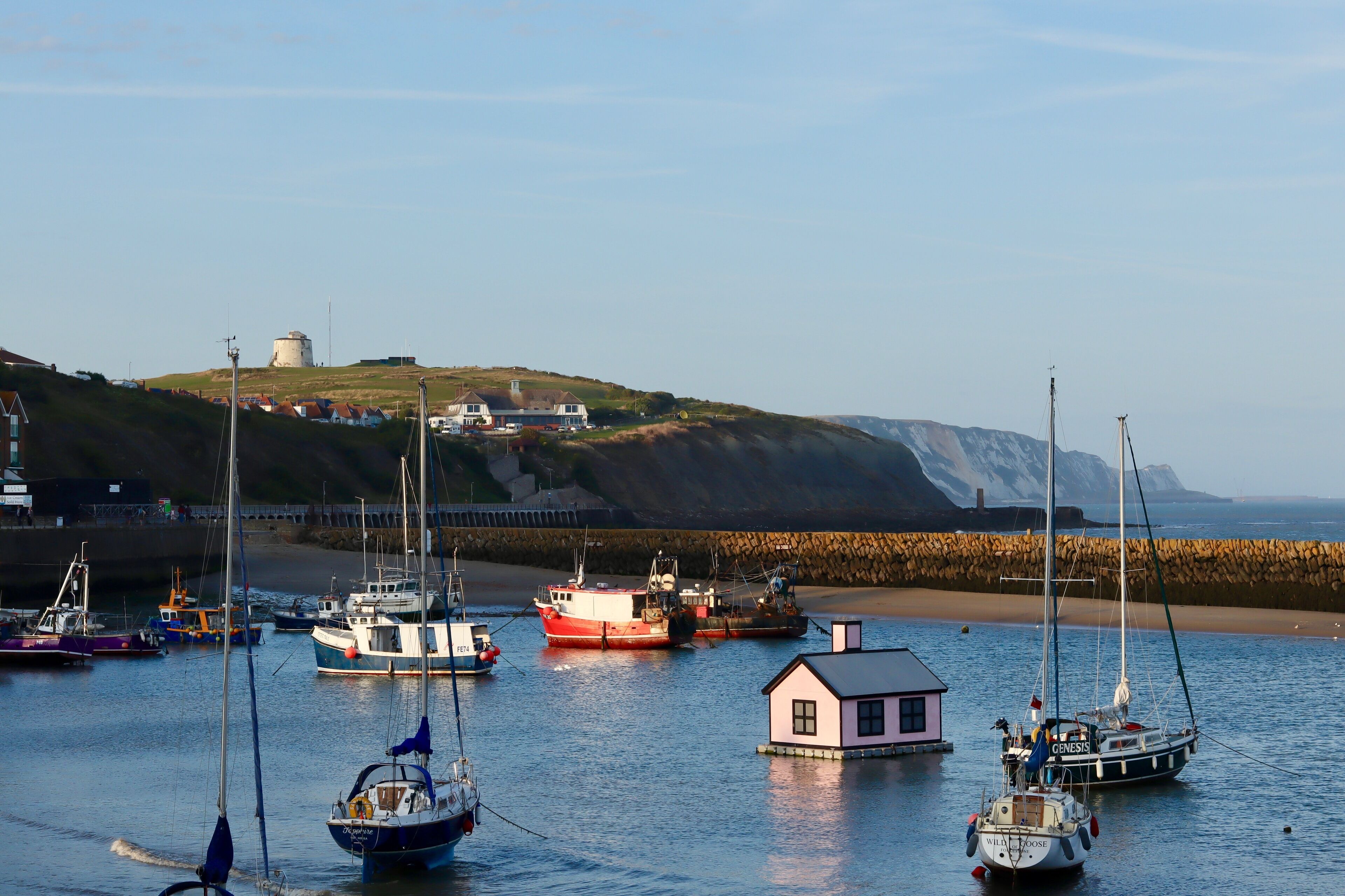 Pink house in the middle of the harbour surrounded by boats