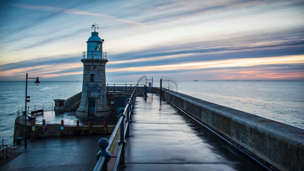 Folkestone's Harbour Arm and Lighthouse at dawn.