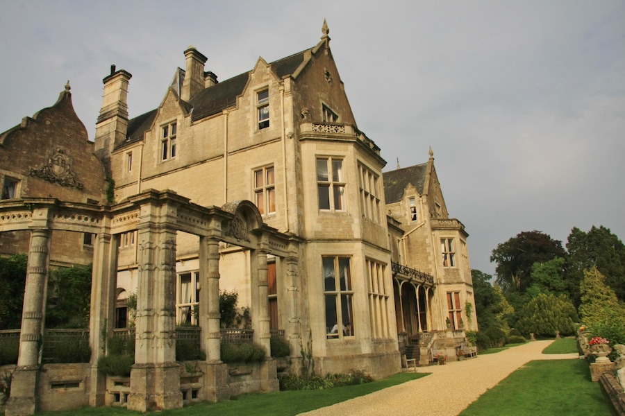 A large, historic stone building with multiple windows and a well-maintained lawn.
