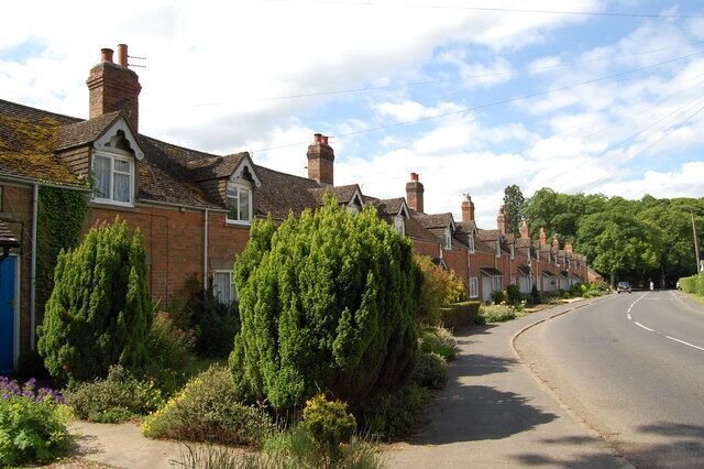 A quiet residential street lined with brick houses, a curved road, and lush greenery.