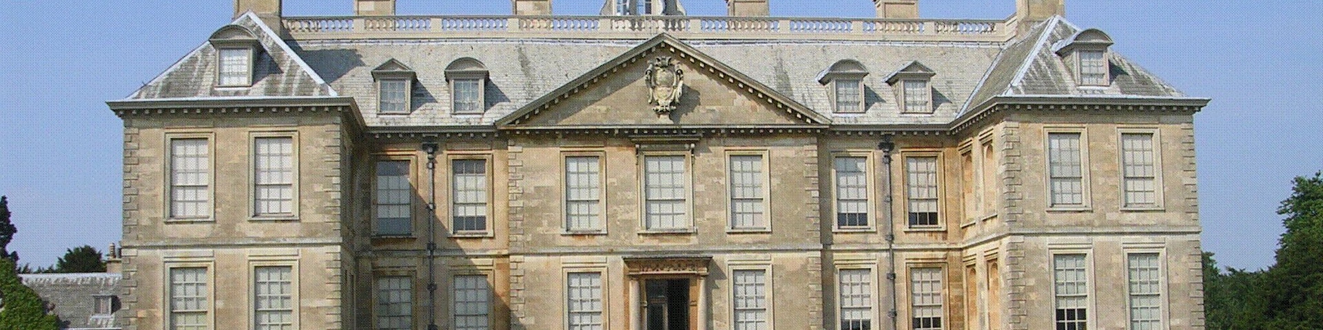 A large, historic building with a symmetrical facade, multiple chimneys, and a central entrance.