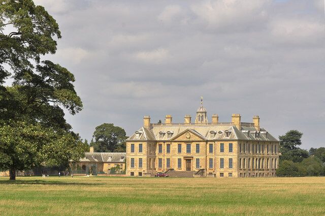 A large stately building with a symmetrical facade, multiple chimneys, and a prominent central tower.