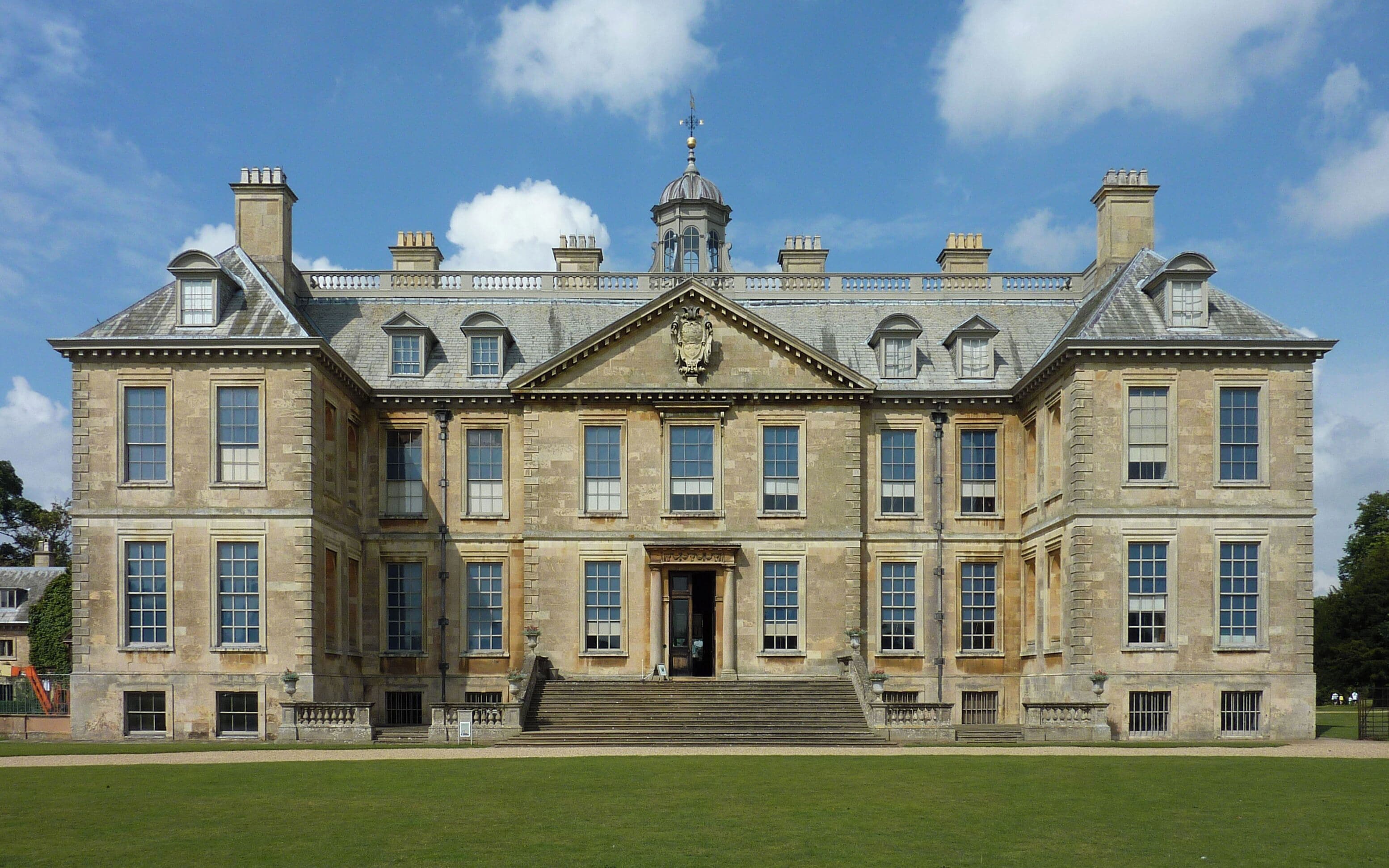 A large, historic stone building with a symmetrical facade, multiple windows, and a central entrance.