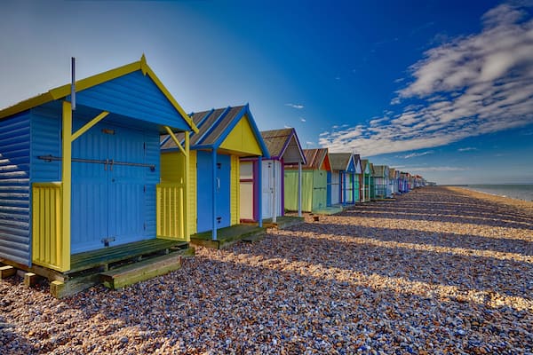 A row of colorful beach huts on a pebbled beach.