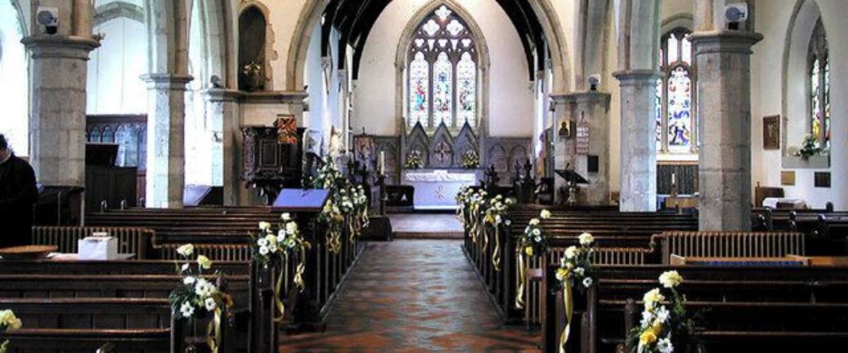 An interior of a church with arched ceilings, pews, and stained glass windows.
