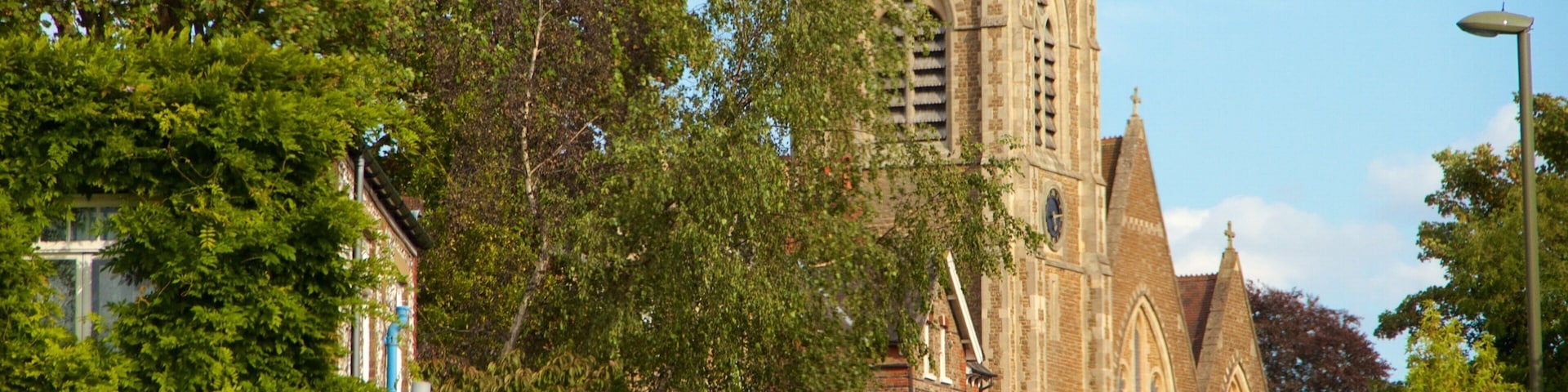 A historic church with a tall spire and intricate architecture, surrounded by lush green trees.
