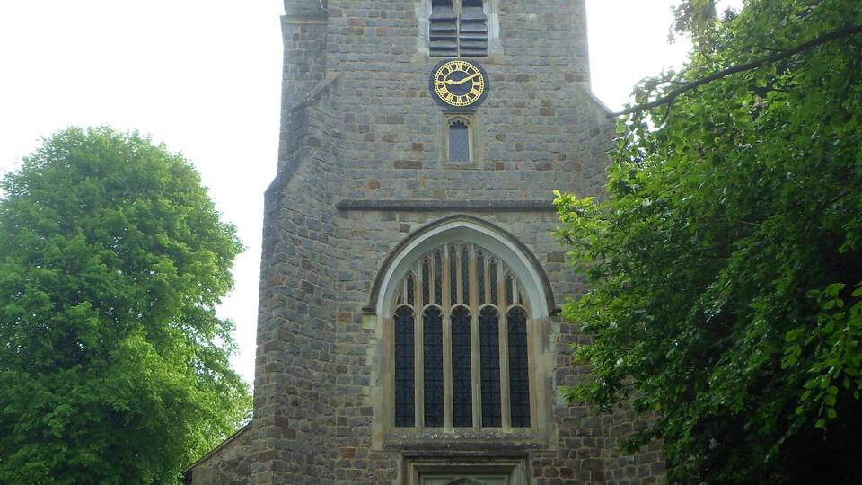 A stone church with a clock tower, arched windows, and a pathway leading to the entrance.