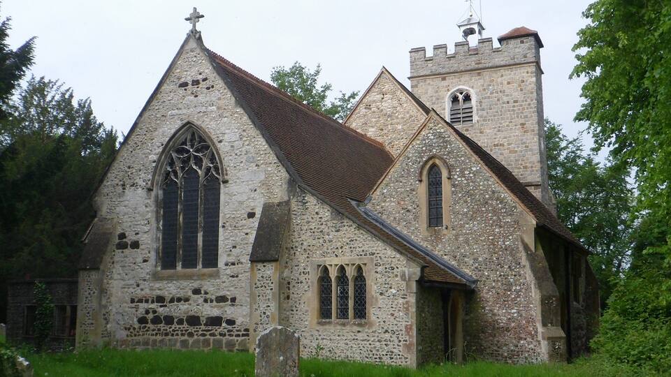 A historic church with a stone facade, a large arched window, and a bell tower.
